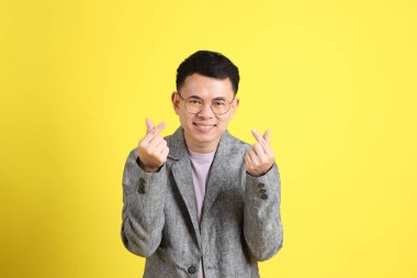 Sarı arka planda gri ceketli Asyalı LGBTQ adamı..