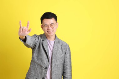 Sarı arka planda gri ceketli Asyalı LGBTQ adamı..