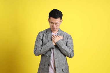 Sarı arka planda gri ceketli Asyalı LGBTQ adamı..