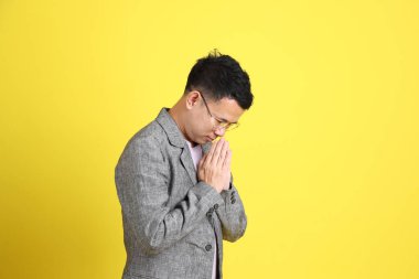 Sarı arka planda gri ceketli Asyalı LGBTQ adamı..