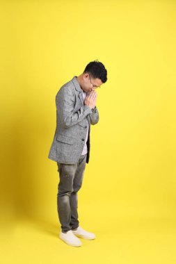 Sarı arka planda gri ceketli Asyalı LGBTQ adamı..