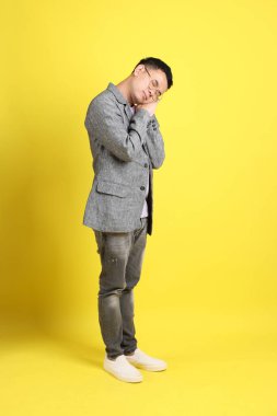 Sarı arka planda gri ceketli Asyalı LGBTQ adamı..