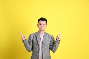 Sarı arka planda gri ceketli Asyalı LGBTQ adamı..