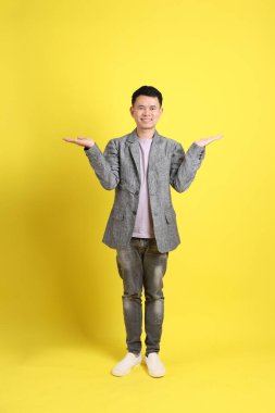 Sarı arka planda gri ceketli Asyalı LGBTQ adamı..