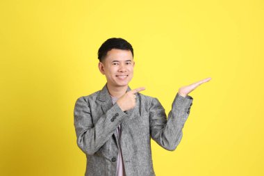 Sarı arka planda gri ceketli Asyalı LGBTQ adamı..