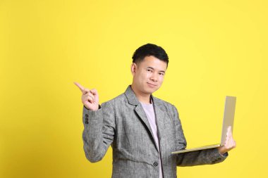 Sarı arka planda gri ceketli Asyalı LGBTQ adamı..