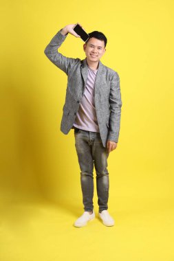 Sarı arka planda gri ceketli Asyalı LGBTQ adamı..