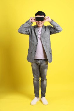 Sarı arka planda gri ceketli Asyalı LGBTQ adamı..