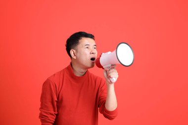 Kırmızı gömlekli Asyalı LGBTQ adam turuncu arka planda duruyor..