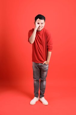 Kırmızı gömlekli Asyalı LGBTQ adam turuncu arka planda duruyor..