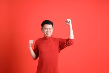 Kırmızı gömlekli Asyalı LGBTQ adam turuncu arka planda duruyor..