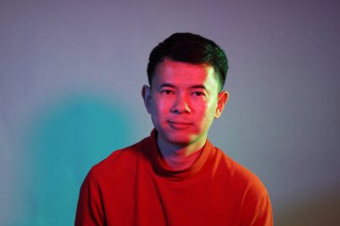 Havalı yetişkin Asyalı adam mavi arka planda, renk jölesinin altında.. 