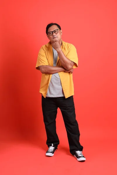 Взрослый Азиат Жёлтой Рубашке Стоит Оранжевом Фоне — стоковое фото