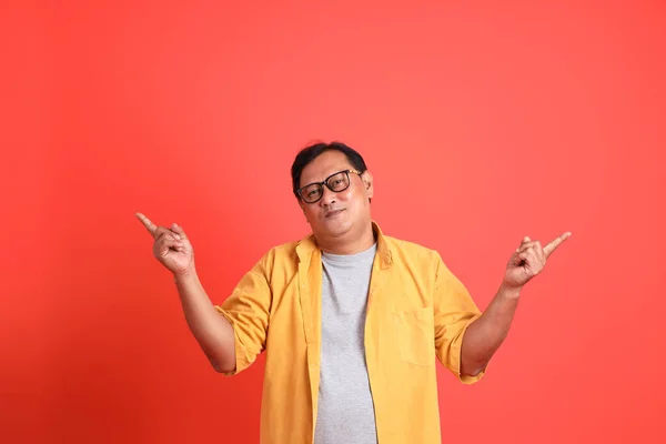 The adult Asian man with yellow shirt standing on the orange background.