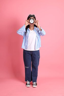 The Asian adult woman with casual clothes standing on the pink background.