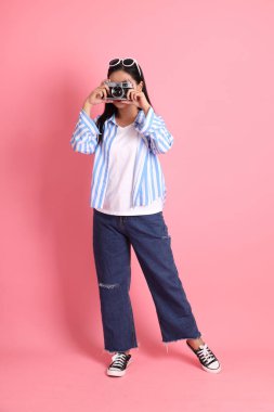 The Asian adult woman with casual clothes standing on the pink background.