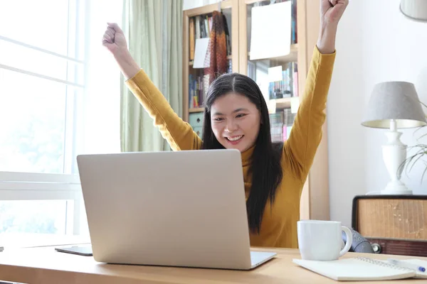 The Asian adult woman working on laptop in her home studio.