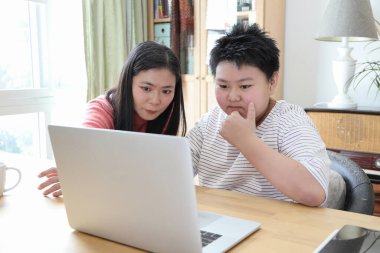 Asyalı bekar anne, oğlunun evde öğrenmesine yardım ediyor..