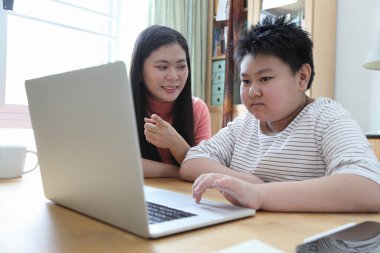 Asyalı bekar anne, oğlunun evde öğrenmesine yardım ediyor..