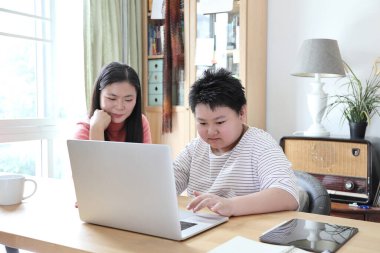 Asyalı bekar anne, oğlunun evde öğrenmesine yardım ediyor..