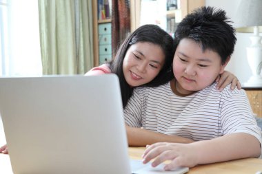 Asyalı bekar anne, oğlunun evde öğrenmesine yardım ediyor..