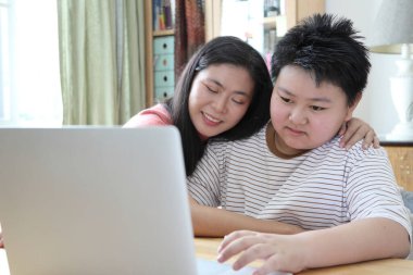 Asyalı bekar anne, oğlunun evde öğrenmesine yardım ediyor..