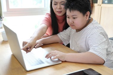 Asyalı bekar anne, oğlunun evde öğrenmesine yardım ediyor..