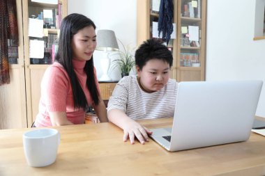 Asyalı bekar anne, oğlunun evde öğrenmesine yardım ediyor..