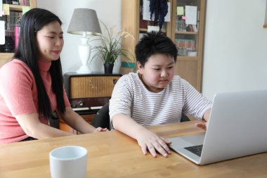 Asyalı bekar anne, oğlunun evde öğrenmesine yardım ediyor..