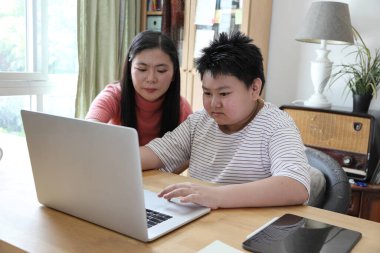 Asyalı bekar anne, oğlunun evde öğrenmesine yardım ediyor..