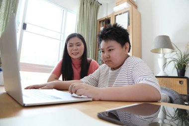 Asyalı bekar anne, oğlunun evde öğrenmesine yardım ediyor..