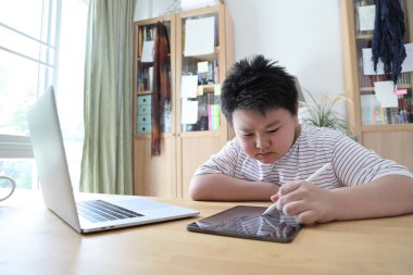 Asyalı çocuk tablete resim çiziyor.. 