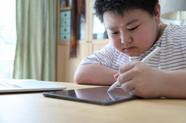 Asyalı çocuk tablete resim çiziyor.. 