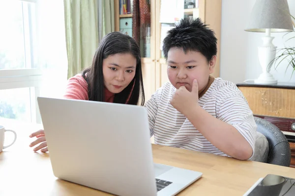 Asyalı bekar anne, oğlunun evde öğrenmesine yardım ediyor..