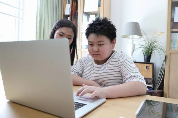 Asyalı bekar anne, oğlunun evde öğrenmesine yardım ediyor..