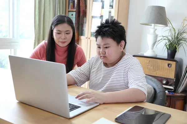 The Asian single mom helping her son to learn from home.