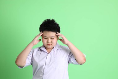 Yeşil arka planda öğrenci üniformalı Asyalı çocuk..