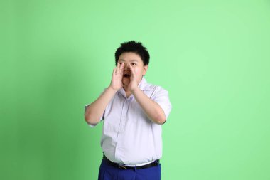 Yeşil arka planda öğrenci üniformalı Asyalı çocuk..