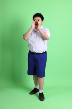 Yeşil arka planda öğrenci üniformalı Asyalı çocuk..