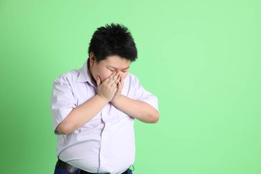 Yeşil arka planda öğrenci üniformalı Asyalı çocuk..