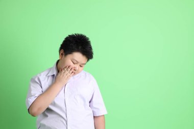 Yeşil arka planda öğrenci üniformalı Asyalı çocuk..