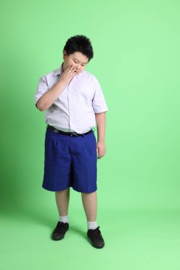 Yeşil arka planda öğrenci üniformalı Asyalı çocuk..