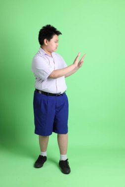 Yeşil arka planda öğrenci üniformalı Asyalı çocuk..