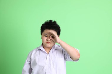 Yeşil arka planda öğrenci üniformalı Asyalı çocuk..