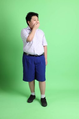 Yeşil arka planda öğrenci üniformalı Asyalı çocuk..