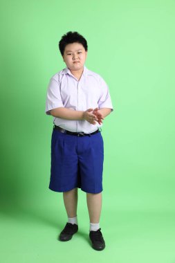 Yeşil arka planda öğrenci üniformalı Asyalı çocuk..