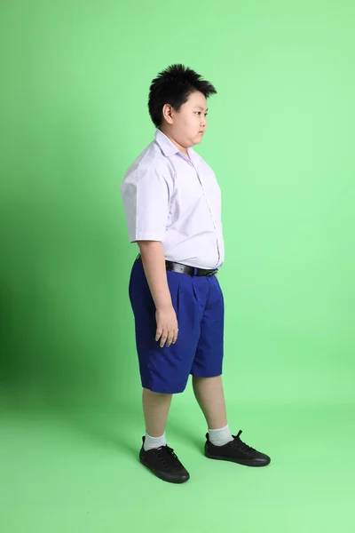 绿色背景上穿着学生服的亚洲男孩 — 图库照片