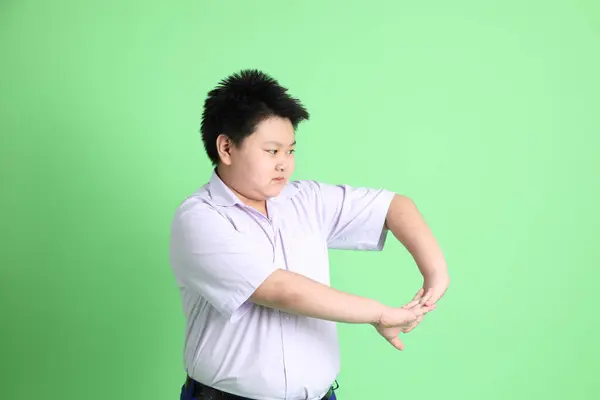 The Asian boy with student uniform on the green background.