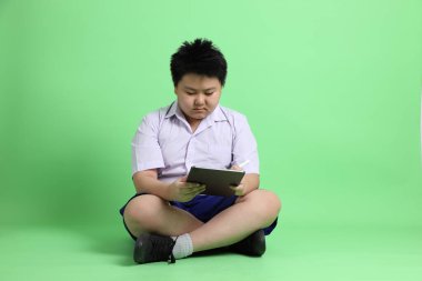 Yeşil arka planda öğrenci üniformalı Asyalı çocuk..