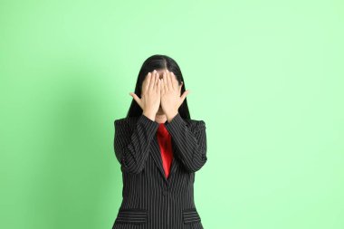 The Asian businesswoman standing on the pastel green background.
